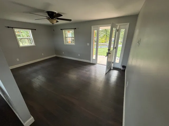 an empty room with wooden floor and windows