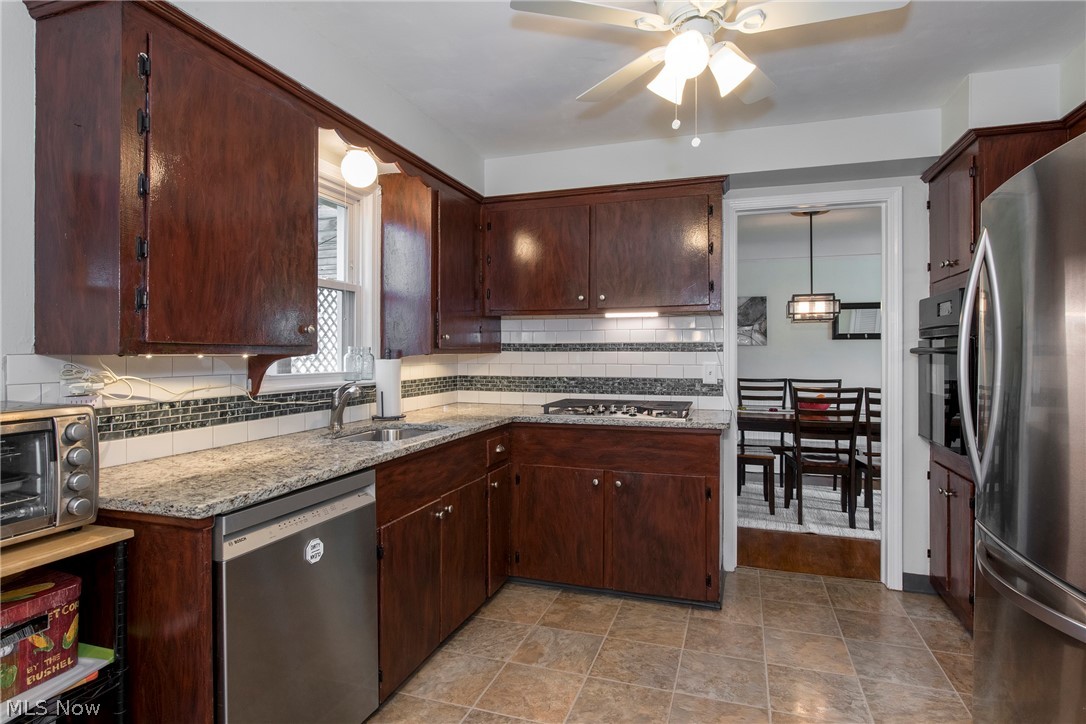 1170 Roland Road Lyndhurst, OH 44124 - Photo 7 of 36 Kitchen featuring sink, light tile floors, appliances with stainless steel finishes, light stone counters, and ceiling fan