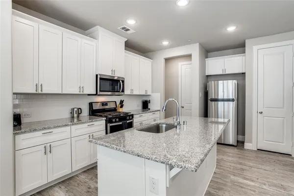 a kitchen with granite countertop white cabinets and stainless steel appliances