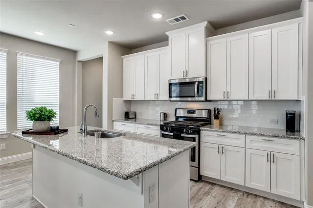 a kitchen with granite countertop white cabinets and a sink