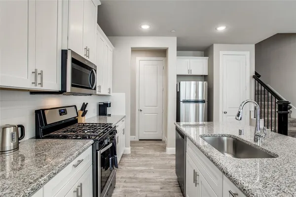 a kitchen with granite countertop a sink stainless steel appliances and cabinets