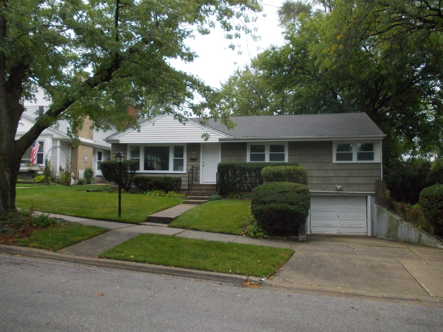 a front view of a house with a garden and trees
