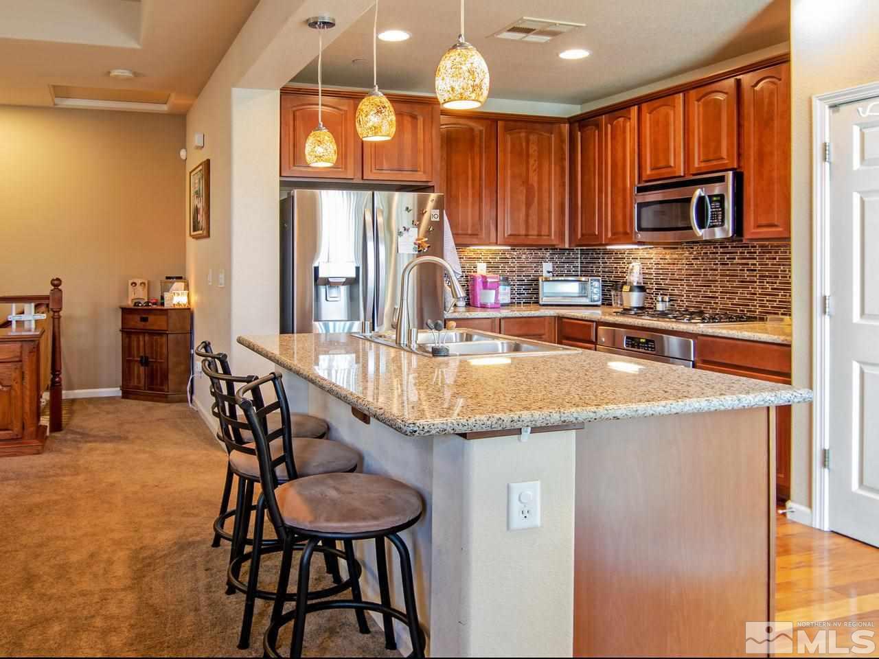 1915 Wind Ranch Road, Unit C Reno, NV 89521 - Photo 7 of 15 a kitchen with granite countertop a table chairs stove and cabinets
