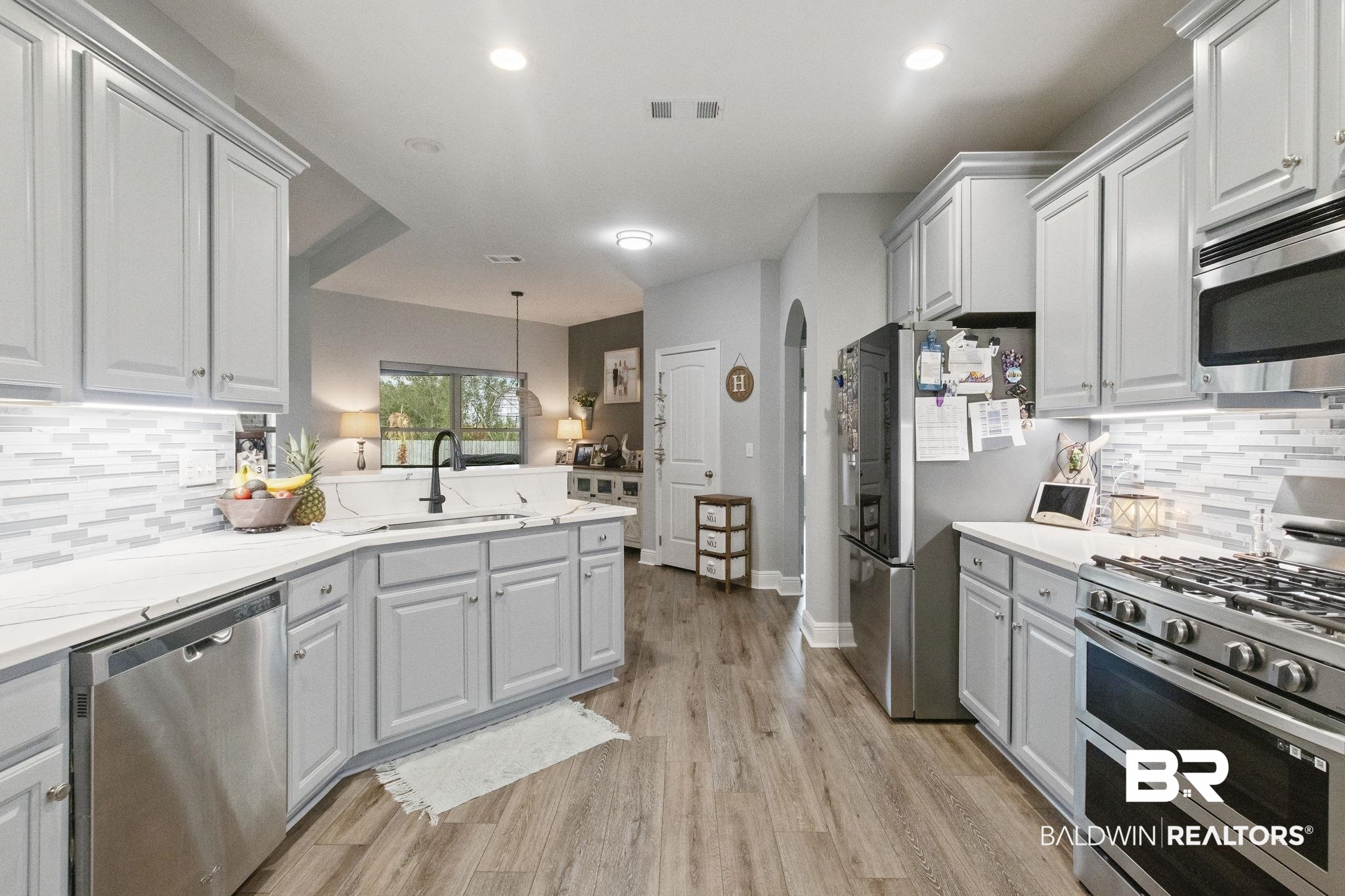 7051 Rocky Rd Loop Gulf Shores, AL 36542 - Photo 7 of 27 Kitchen with visible vents, light wood finished floors, arched walkways, a sink, and stainless steel appliances