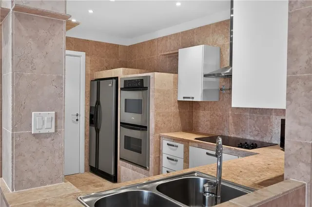 a kitchen with stainless steel appliances granite countertop a sink and a refrigerator