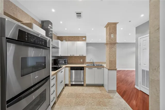 a kitchen with stainless steel appliances granite countertop a refrigerator a stove and a sink