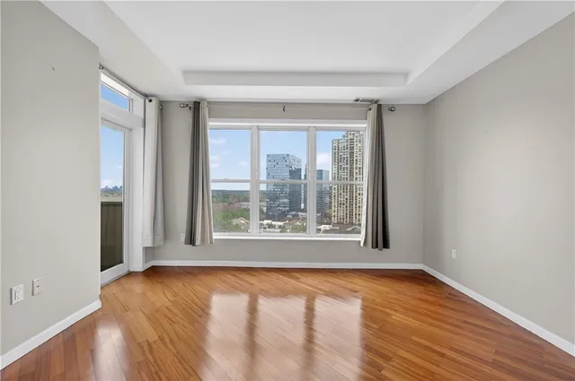 a view of an empty room with wooden floor and a window