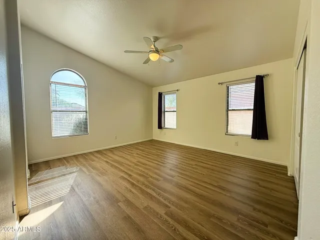 a view of an empty room with window and wooden floor
