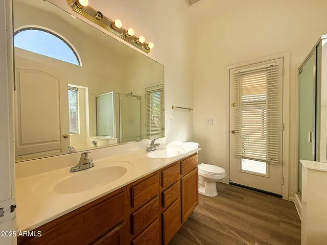 a bathroom with a double vanity sink a toilet and a large mirror