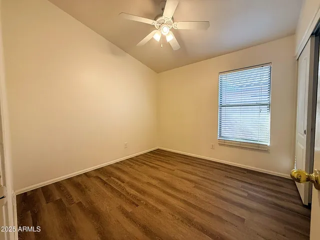 a view of an empty room with a window and wooden floor