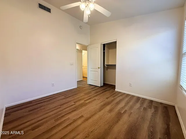 an empty room with an entryway and chandelier fan