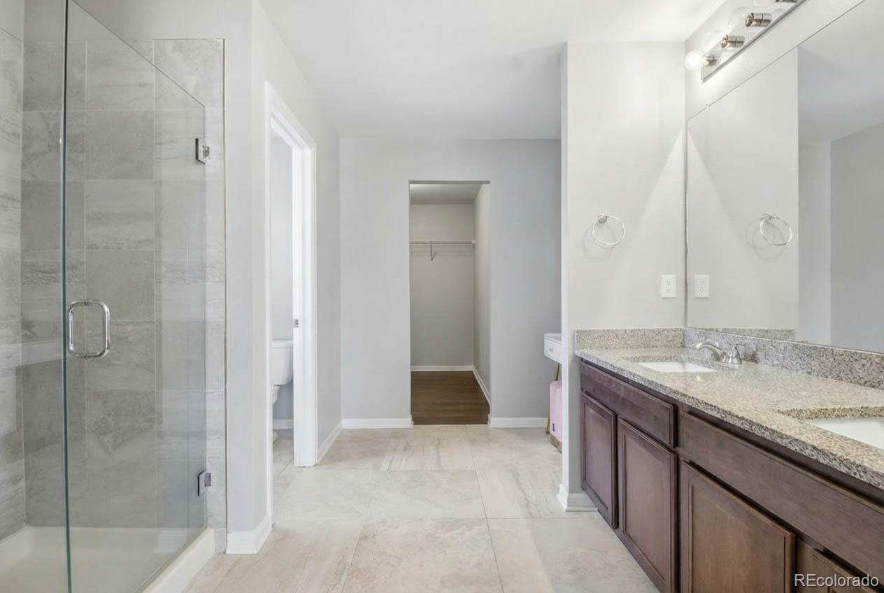 16343 East 100th Way Commerce City, CO 80022 - Photo 11 of 31 a bathroom with a granite countertop sink a mirror and a shower