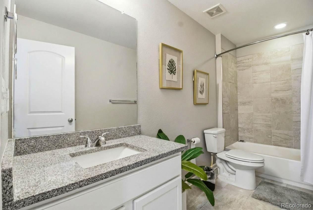 16343 East 100th Way Commerce City, CO 80022 - Photo 15 of 31 a bathroom with a granite countertop sink a toilet and a mirror