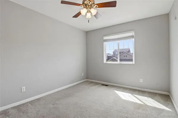 an empty room with chandelier fan and windows