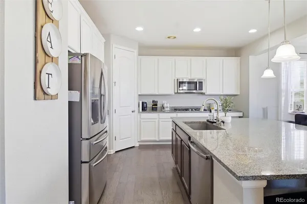 a kitchen with stainless steel appliances granite countertop a refrigerator a sink and a stove