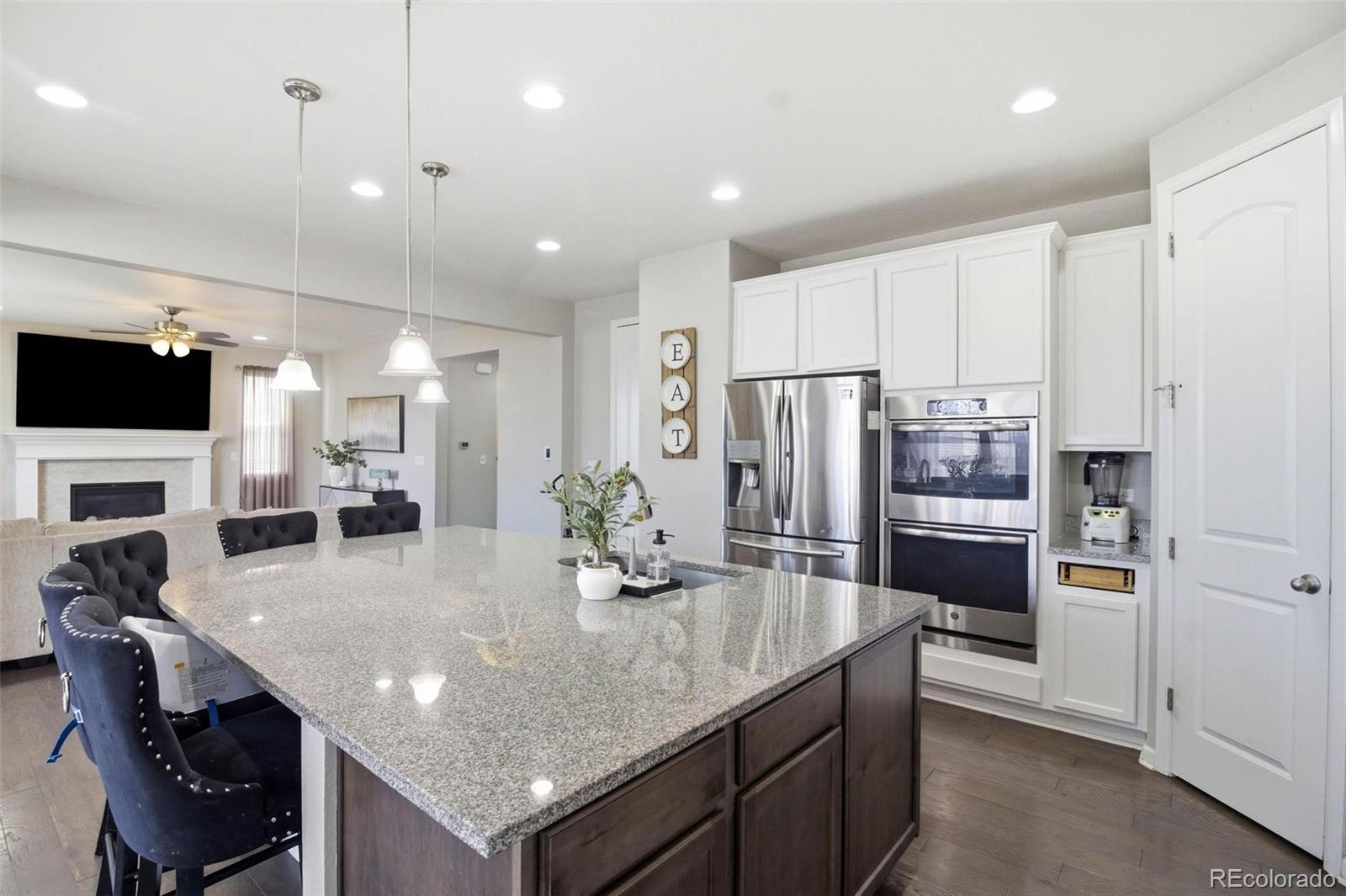 16343 East 100th Way Commerce City, CO 80022 - Photo 7 of 31 a kitchen with stainless steel appliances granite countertop a kitchen island a stove a refrigerator a oven a sink a dining table and chairs with wooden floor