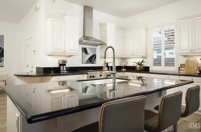 a kitchen with stainless steel appliances granite countertop a sink a stove and white cabinets