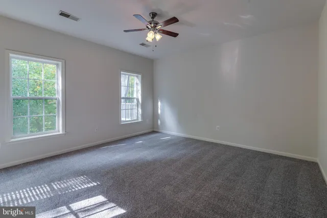 an empty room with windows and fan