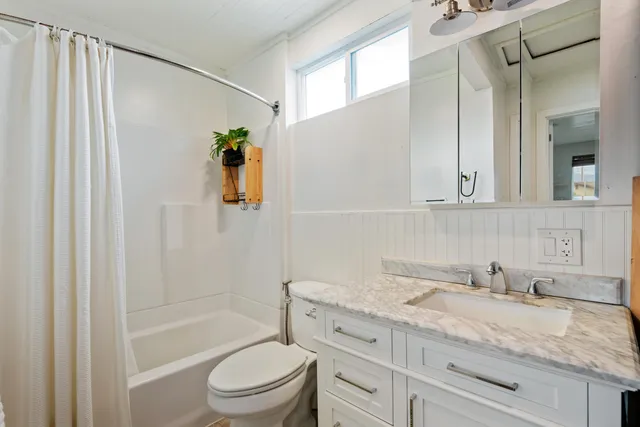 a bathroom with a granite countertop sink toilet and shower