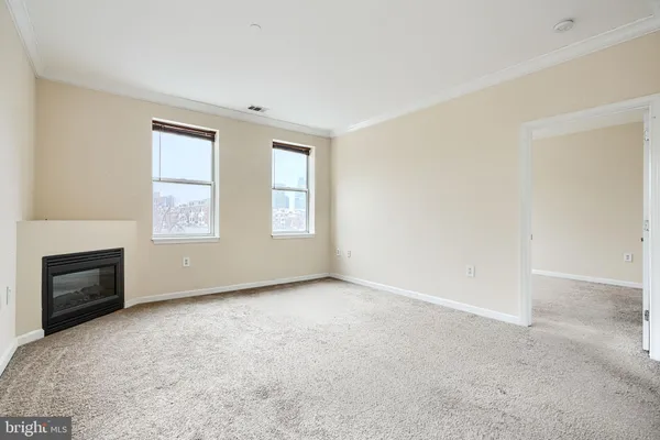 an empty room with windows and fireplace