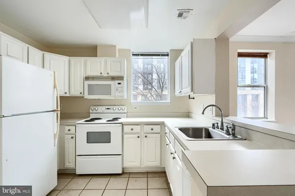 a kitchen with white cabinets sink and white appliances