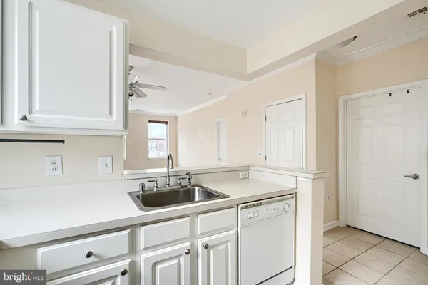 a kitchen with stainless steel appliances granite countertop a sink a refrigerator and white cabinets with wooden floor