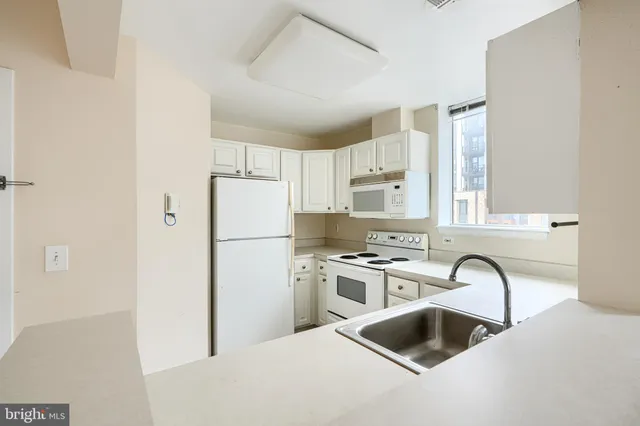 a kitchen with stainless steel appliances granite countertop a refrigerator sink and white cabinets