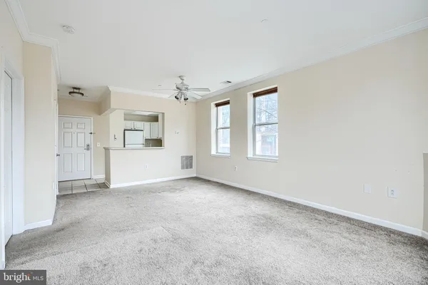 an empty room with chandelier fan and windows