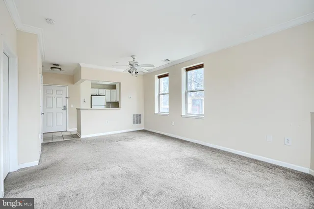 an empty room with chandelier fan and windows