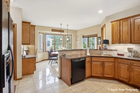 a kitchen with granite countertop a refrigerator cabinets and chairs