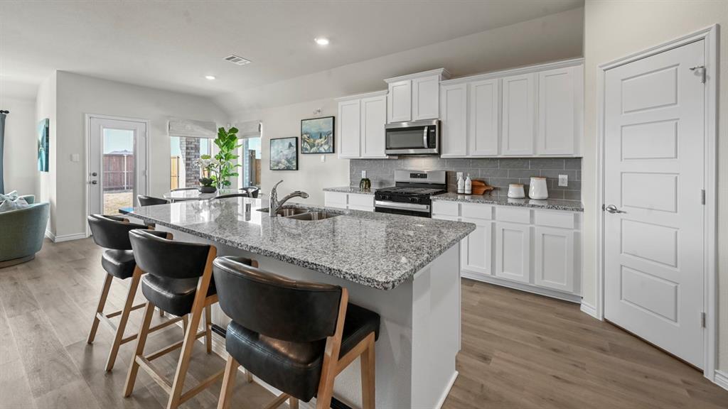 4020 Red Blf Street Pilot Point, TX 76258 - Photo 14 of 39 a kitchen with granite countertop kitchen island white cabinets and stainless steel appliances