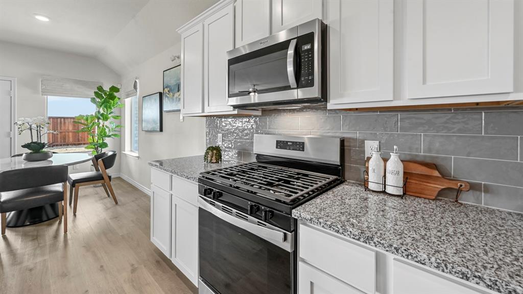 4020 Red Blf Street Pilot Point, TX 76258 - Photo 18 of 39 a kitchen with stainless steel appliances granite countertop a stove a sink and a microwave