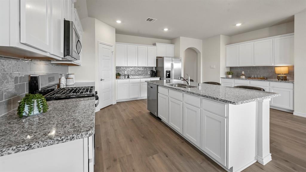 4020 Red Blf Street Pilot Point, TX 76258 - Photo 20 of 39 a kitchen with stainless steel appliances granite countertop wooden cabinets a stove top oven a sink and dishwasher
