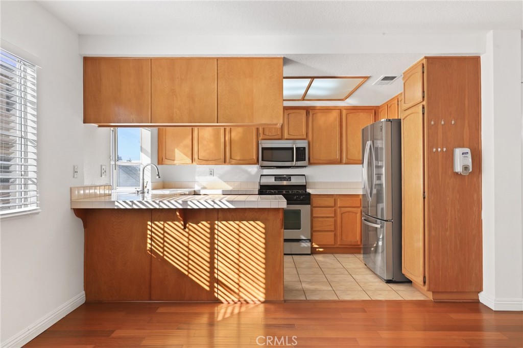 2300 Maple Avenue, Unit 26 Torrance, CA 90503 - Photo 9 of 30 a kitchen with stainless steel appliances granite countertop a refrigerator a sink dishwasher a stove with wooden cabinets and floor