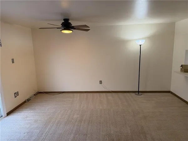 a view of an empty room with kitchen and a fireplace