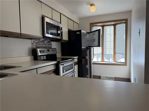 a view of kitchen and an empty room with wooden floor