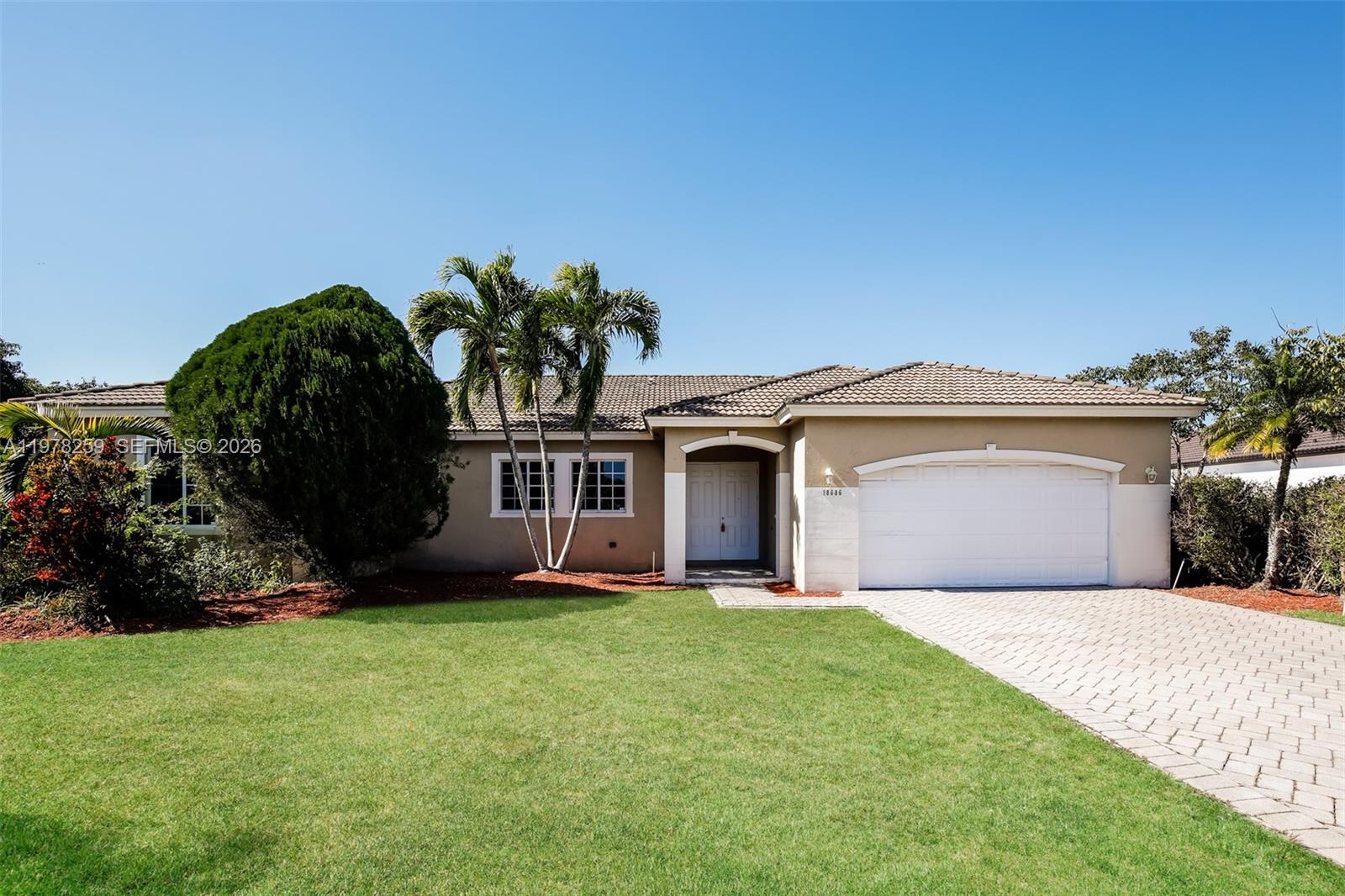 a front view of a house with a garden and trees