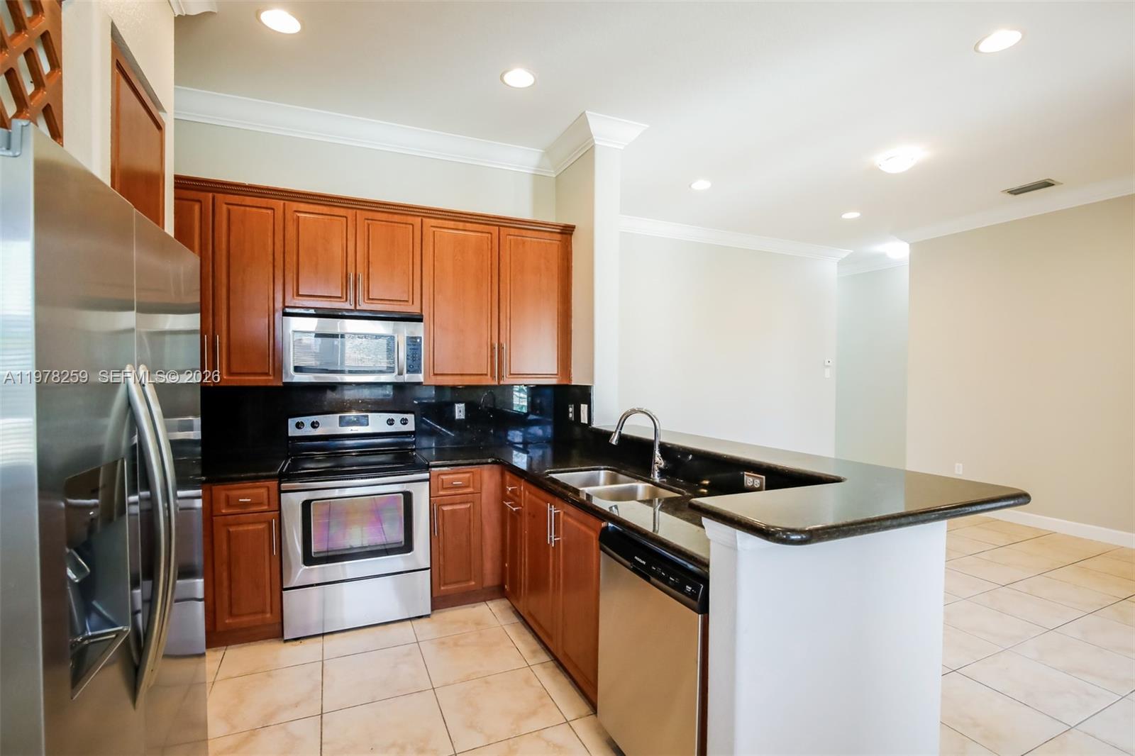 18686 Southwest 132nd Avenue Miami, FL 33177 - Photo 9 of 18 a kitchen with stainless steel appliances granite countertop a sink stove and refrigerator