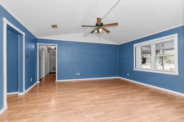 a view of an empty room with window and wooden floor