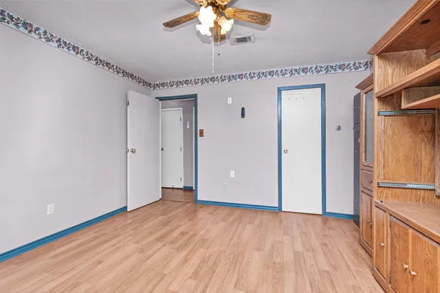 a view of a livingroom with a chandelier fan and wooden floor