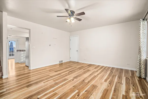 an empty room with wooden floor and a ceiling fan