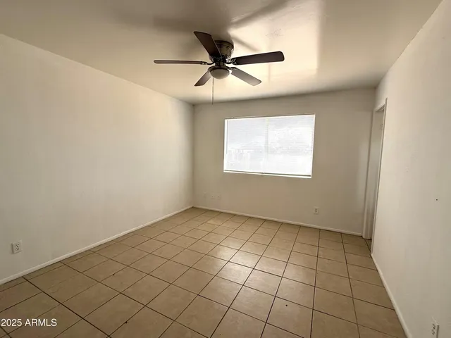 an empty room with windows and fan