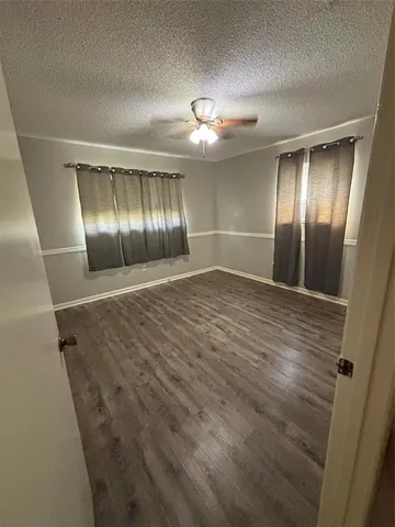 an empty room with wooden floor and hallway with wooden floor