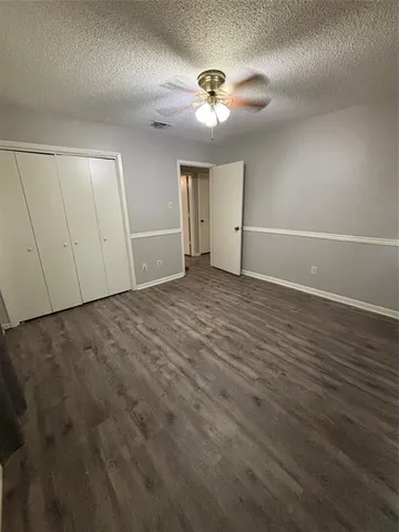 an empty room with wooden floor chandelier fan and windows