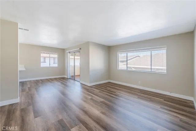 a view of an empty room with wooden floor and window