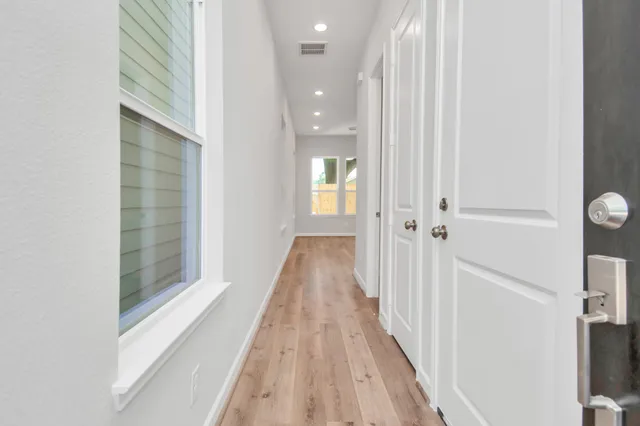 a view of a hallway with wooden floor and a bathroom