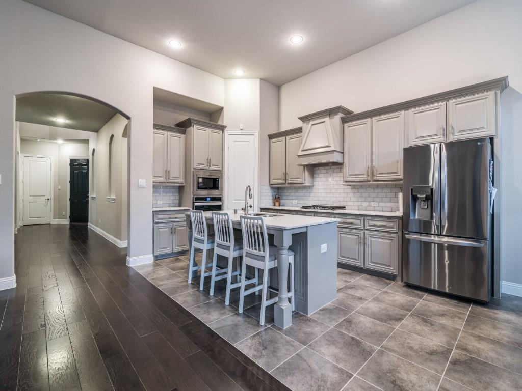 3323 Royal Ridge Drive Rockwall, TX 75087 - Photo 13 of 40 Kitchen with stainless steel appliances, gray cabinetry, custom range hood, arched walkways, and recessed lighting