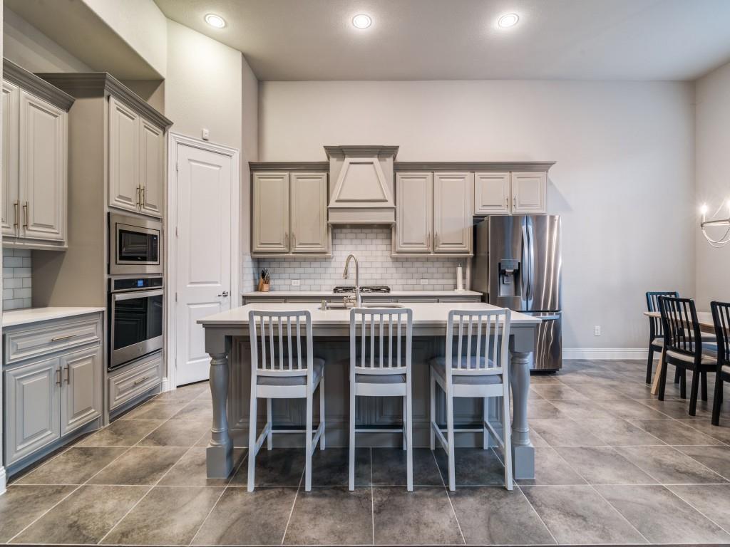 3323 Royal Ridge Drive Rockwall, TX 75087 - Photo 14 of 40 Kitchen featuring appliances with stainless steel finishes, gray cabinets, custom exhaust hood, an island with sink, and tasteful backsplash