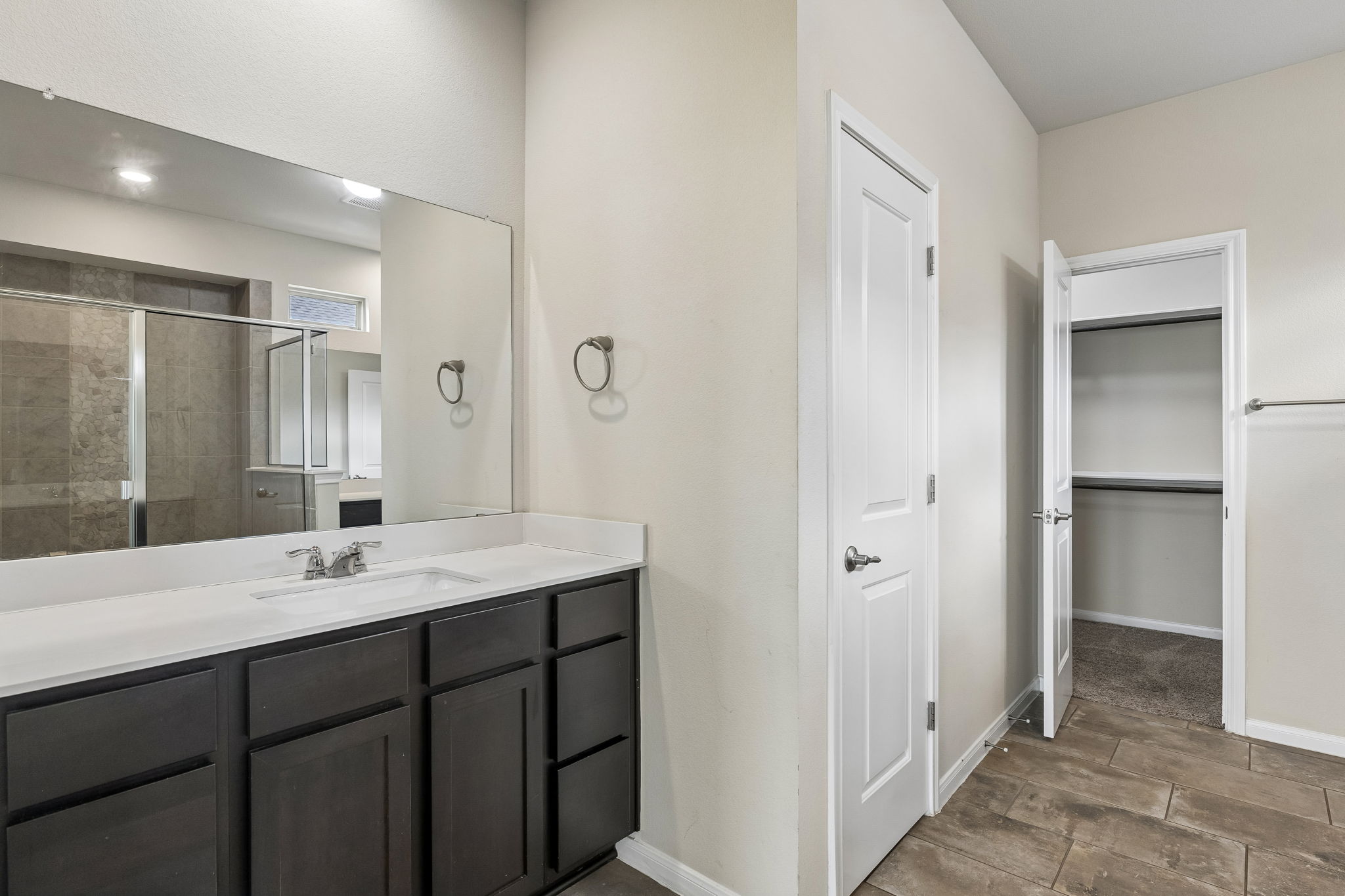 301 Rimrock Court Bastrop, TX 78602 - Photo 13 of 21 A well-appointed bathroom features a dark wood vanity with white countertops and a large mirror.