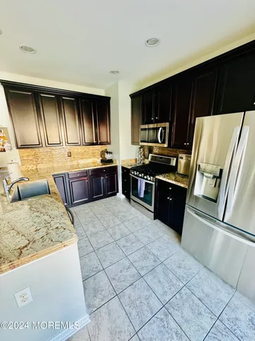 a kitchen with stainless steel appliances granite countertop a stove a sink and a refrigerator